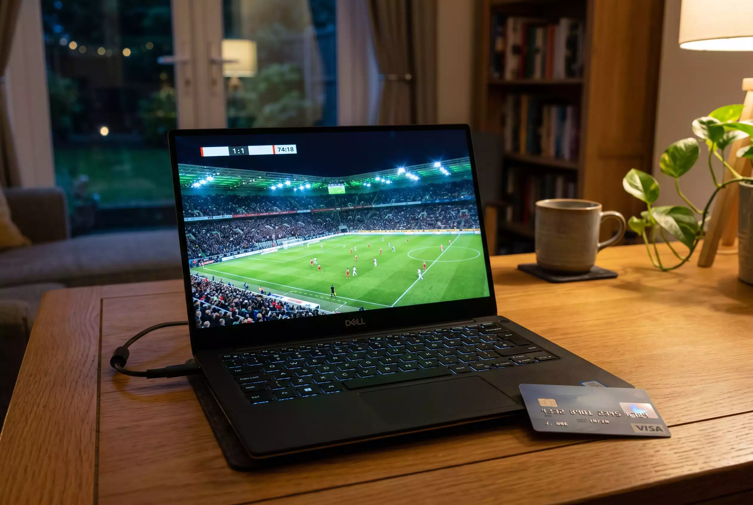 Laptop mit einem laufenden Fußballspiel auf dem Bildschirm neben einer Kreditkarte