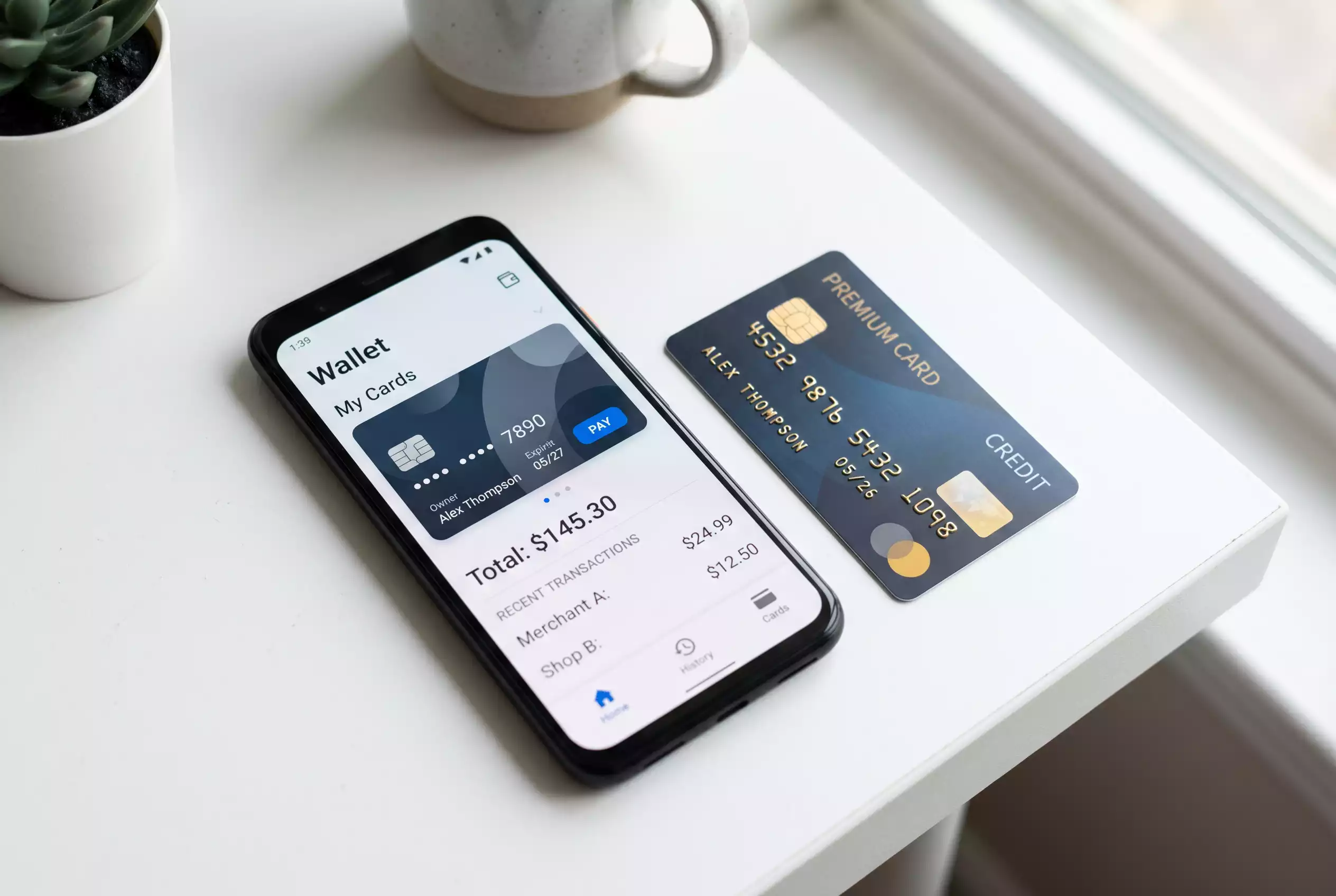 Smartphone mit einer digitalen Wallet-App und einer Kreditkarte daneben