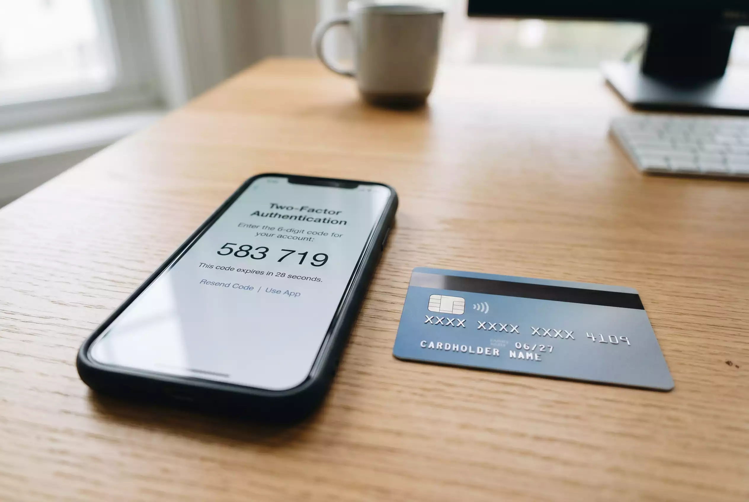 Smartphone mit einem Sicherheitscode neben einer Kreditkarte auf einem Schreibtisch